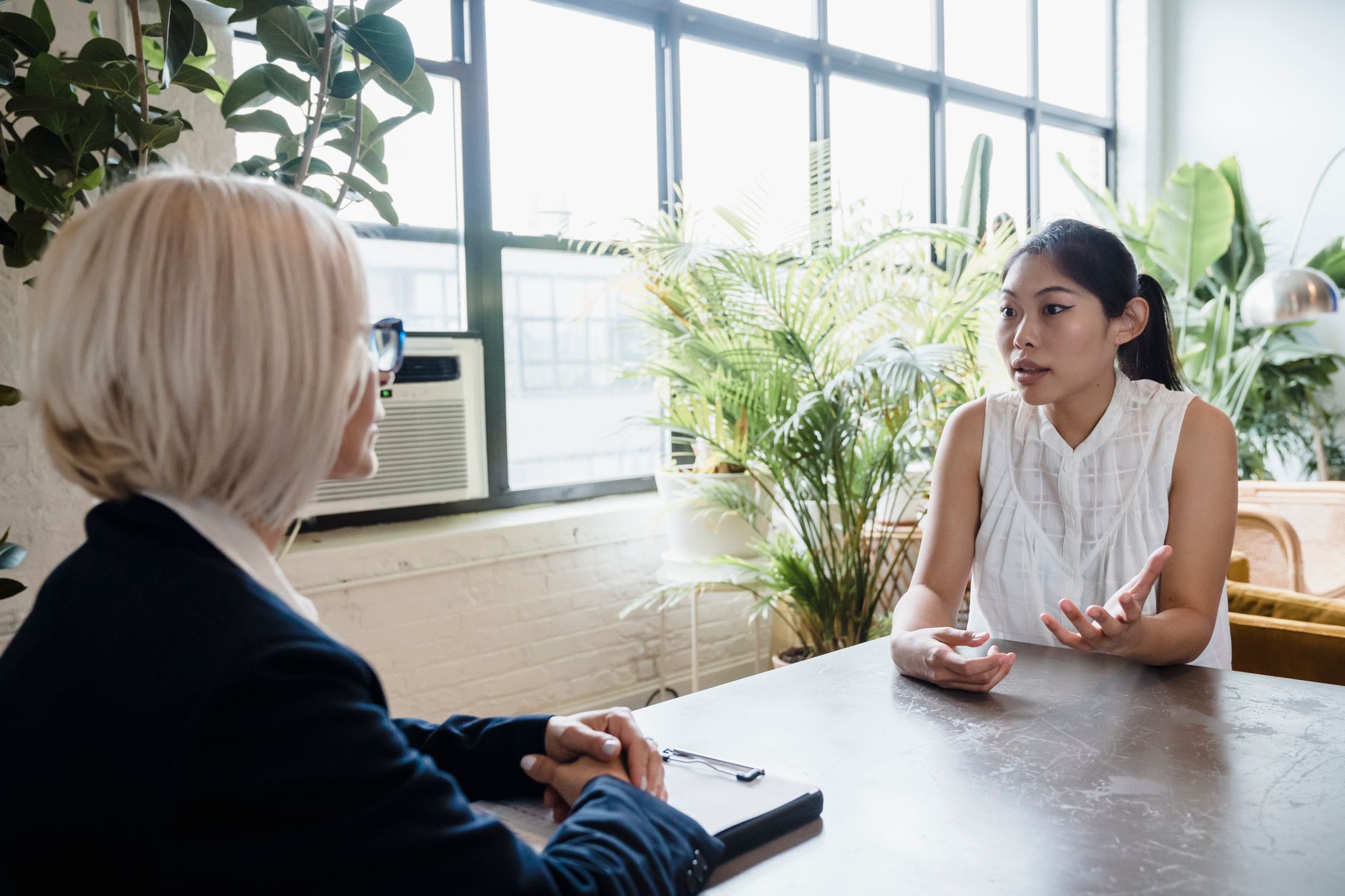 A therapist listening closely to a client in a warm, plant-filled room